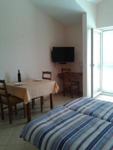 a bedroom with a table and a tv and a bed at Apartments Delfini in Sveti Filip i Jakov