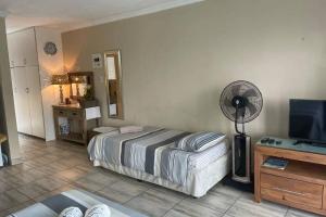 a bedroom with a bed and a desk with a fan at Anju@Beach in Margate