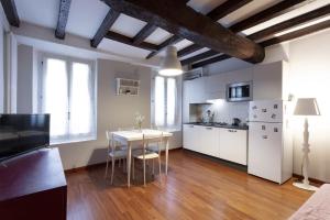 eine Küche mit weißen Schränken und einem Tisch mit Stühlen in der Unterkunft Rua Freda Apartments in Modena