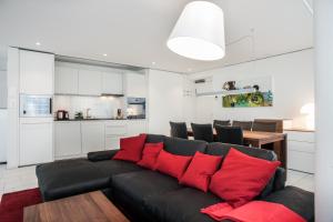 ein Wohnzimmer mit einem schwarzen Sofa und roten Kissen in der Unterkunft CITY STAY - Zugerstrasse in Cham