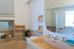 bagno con vasca, lavandino e specchio di Villa Castello Apartments a Capri