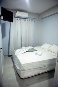 a white bed in a room with a window at Hotel Mamma Mia in Aparecida