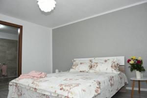 een witte slaapkamer met een bed met bloemen erop bij CASA DIN SAT in Eşelniţa