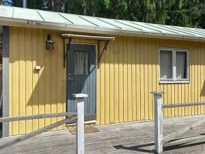 ein kleines gelbes Gebäude mit einer Tür und einer Veranda in der Unterkunft 6 person holiday home in BOTTNARYD in Bottnaryd