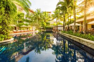 a pool at a resort with palm trees at The Chava Resort in Surin Beach
