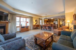 a living room with couches and a table and a kitchen at Two Bedroom Condo with Balcony over Mountaineer Square - Just Steps from the Slopes! condo in Crested Butte