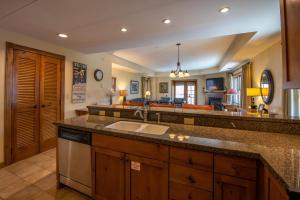 a kitchen with a sink and a living room at Two Bedroom Condo with Balcony over Mountaineer Square - Just Steps from the Slopes! condo in Crested Butte