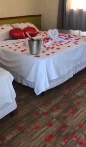 a bed with red hearts on it with a table with a bucket at QUINZE HOTEL & POUSADA in Bataguaçu