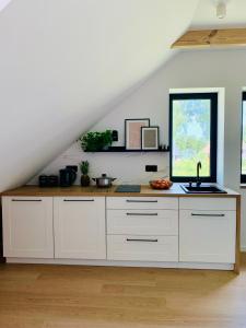 a kitchen with white cabinets and a large window at Apartamenty KAHOY balia pomost Kozin in Kozin +13 photos