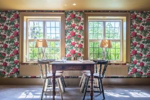 a dining room with a table and three windows at The Crown Inn in Stoke by Nayland