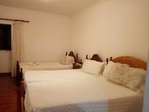 ein Schlafzimmer mit zwei Betten mit weißer Bettwäsche in der Unterkunft O ROCHA in Paredes do Rio