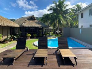 a deck with chairs next to a swimming pool at Muri Beach Hideaway - Adults Only in Rarotonga