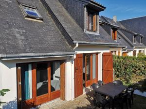 an extension to a house with wooden doors and a table at Les baigneurs in Merville-Franceville-Plage