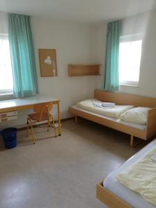 une chambre avec deux lits, un bureau et une chaise dans l'établissement Gästehaus Goethe-Institut Schwäbisch Hall, à Schwäbisch Hall