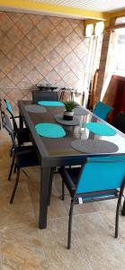 ein Tisch mit blauen Stühlen und ein Tisch mit einer Pflanze darauf in der Unterkunft bas de VILLA LARCHER avec piscine in Le Marin