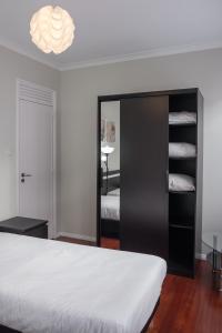 a bedroom with a white bed and a black closet at Apartamentos Portodouro - Ribeira in Porto