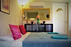 1 dormitorio con 1 cama con almohadas rosas y azules en KultúrÉlet Vendégháza, en Kétegyháza