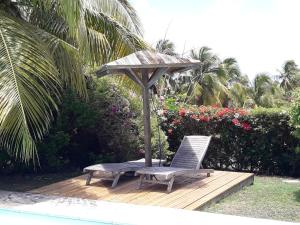 une chaise et un parasol sur une terrasse en bois dans l'établissement Villas Karukera - Hamak Coco Caraibes, à Kahouanne