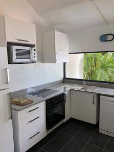 La cuisine est équipée de placards blancs, d'un évier et d'un four micro-ondes. dans l'établissement Villas Karukera - Hamak Coco Caraibes, à Kahouanne