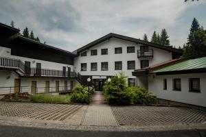 a white building with a walkway in front of it at Hotel Bohemia in Železná Ruda