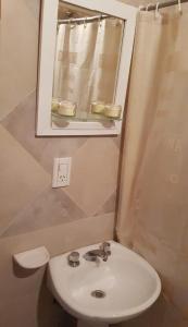uma casa de banho com um lavatório branco e um espelho. em Canelo departamento em Ushuaia