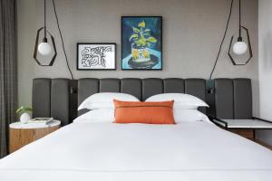um quarto com uma grande cama branca e uma almofada laranja em Kimpton - Harper Hotel, an IHG Hotel em Fort Worth