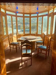 a dining room with a table and chairs and windows at Taimoor Hotel swat Kalam in Kalām