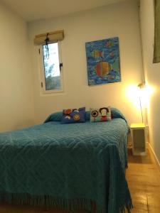 ein Schlafzimmer mit einem Bett mit einer blauen Decke in der Unterkunft El Trotamundos in Puerto Pirámides