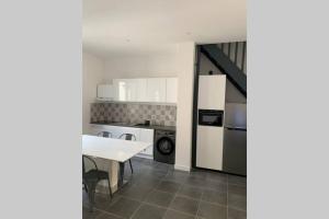 eine Küche mit weißen Schränken und einem Tisch und einem Herd in der Unterkunft Maison de charme in Montagnac