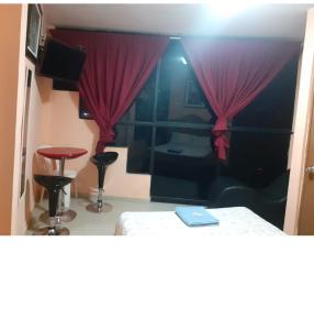 Habitación con cama y cortina roja en Hospedaje Las Palmeras, en Piura