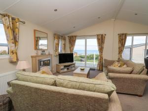 a living room with two couches and a television at The Potting Shed in New Quay