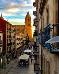una calle de la ciudad con mesas y sombrillas y una catedral en Residencial Europa, en Salamanca
