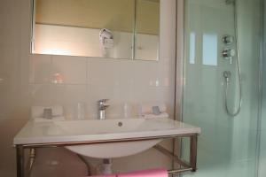 La salle de bains blanche est pourvue d'un lavabo et d'une douche. dans l'établissement Logis hôtel Le Terminus, à Bourcefranc