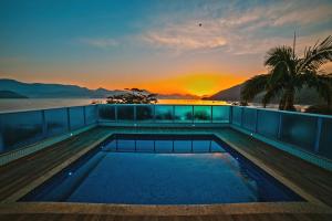 Una piscina en la azotea de un edificio con la puesta de sol. en Ubatuba Praia Hotel, en Ubatuba