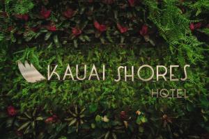 a sign that reads kauai shoes hotel is covered in plants at Kauai Shores Hotel in Kapaa