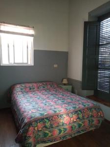 a bedroom with a bed with a colorful bedspread and a window at La Casa del Molino in Ramallo