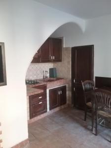 cocina con armarios de madera, mesa y silla en Casa Graziella, en SantʼAgata di Militello