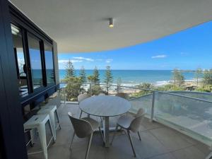 a table and chairs on a balcony with the ocean at Breeze 801 in Mooloolaba