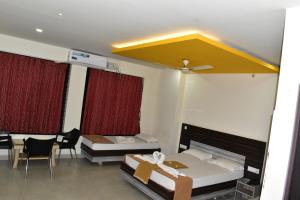 Pokój z 2 łóżkami, stołem i krzesłami w obiekcie Dharwad Residency w mieście Dharwad