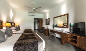 Habitación de hotel con cama, TV, cama y escritorio. en Earls Rajarata en Anuradhapura