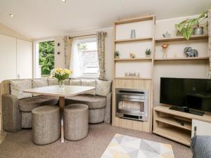 a living room with a table and a tv at Ochenta in Combe Martin