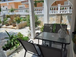 um pátio com uma mesa, cadeiras e vasos de plantas em Villa Pappas em Parga