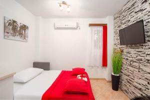 Apartment Kokolo في سبليت: غرفة نوم بسرير احمر وتلفزيون على جدار من الطوب