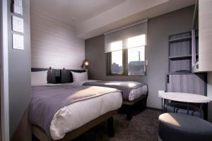 a hotel room with two beds and a window at Joytel Hotel Namba Dotonbori in Osaka