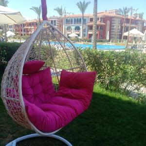 a hanging chair with two pillows in front of a pool at شاليهات بورتو مطروح فيو بحر Porto Matrouh Sea View Families Only in Marsa Matruh