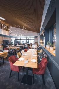 un restaurant avec des tables en bois et des chaises rouges dans l'établissement Hôtel Bastide, à Onet le Château