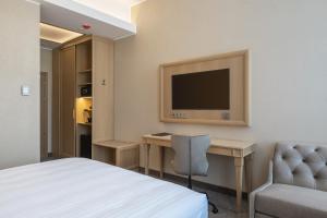 a hotel room with a bed and a desk and a television at CALVARY Hotel & Restaurant Vilnius in Vilnius
