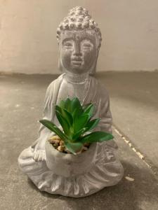 una estatua de un buddha sosteniendo una planta en Les Jardins d'Élise, calme et verdure à Lure, en Lure