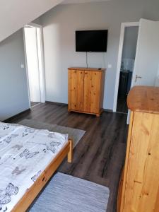 a bedroom with a bed and a flat screen tv at Családbarát apartman in Vonyarcvashegy