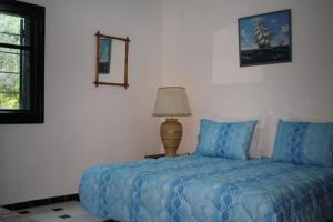 Schlafzimmer mit einem Bett mit blauer Bettwäsche und einer Lampe in der Unterkunft Propriete Etoile De Mer in Skhirat